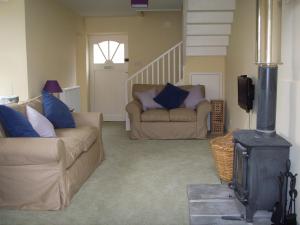 a living room with two couches and a wood stove at Cumledge Yew Trees Cottage in Duns