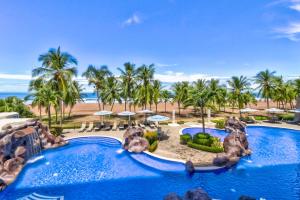 una imagen de una piscina del complejo con palmeras y una playa en Diamante del Sol 203S en Jacó