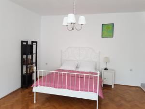 シビウにあるLuk Old Town Apartmentの白いベッド(ピンクと白のシーツ付)