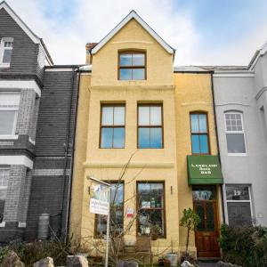 a yellow building with a green sign in front of it at Langland Road B&B in The Mumbles