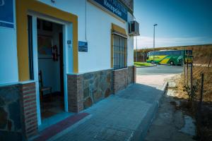 una puerta a un edificio con un coche aparcado en un aparcamiento en Pensión Montero, en Jedula