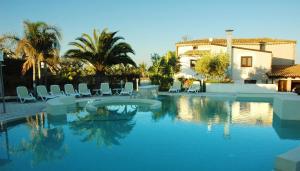 a swimming pool with chairs and a house in the background at Agriturismo Baglio San Nicola in Naro