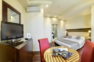 una camera d'albergo con letto, televisore e tavolo di Hotel Vittoria a Faenza