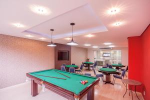 a pool table in a room with tables and chairs at Hotel Paraiso in Piratuba