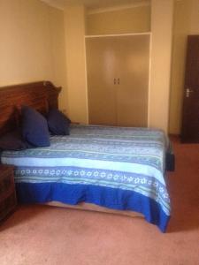 a bedroom with a bed with blue sheets and a closet at Pilot Inn Accommodation in Kempton Park +47 photos