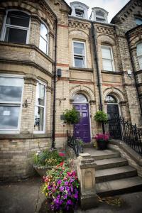 a brick house with a purple door and some flowers at Moorgarth Guesthouse in York