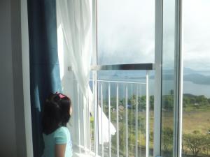 a little girl looking out a window at the ocean at Wind Residences Tower 4 in Tagaytay