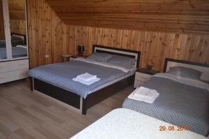 two beds in a room with wooden walls and wooden floors at Country House v Kleynikah in Brest