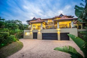 uma casa grande com uma entrada em frente em Zimbali Holiday Home-22 Acaciawood em Ballito