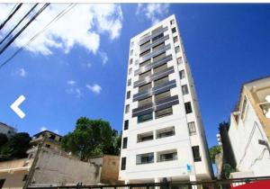 a tall white building in front of a blue sky at Apartamento 2 Quartos vista mar in Salvador