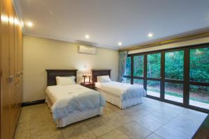 a bedroom with two beds and a large window at Zimbali Holiday Home-22 Acaciawood in Ballito