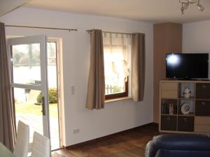 ein Wohnzimmer mit einer Glasschiebetür und einem TV in der Unterkunft Ferienwohnung Rohrwallinsel Köpenick in Berlin