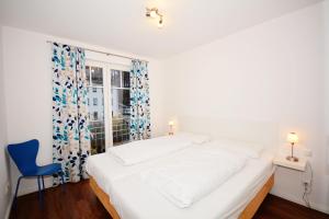 um quarto com uma cama branca e uma cadeira azul em Komfort-Ferienwohnung Rosa Nr. 6 by Meer-Ferienwohnungen em Ostseebad Sellin