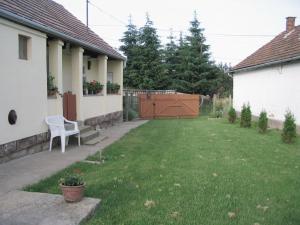 a yard with a white chair and a house at Marika Vendégház in Mátraderecske