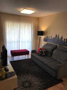 a living room with a gray couch and a window at Charmoso Apartamento no Bairro Jardim in Santo André