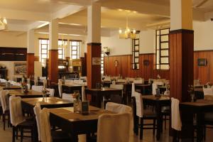 a restaurant with wooden tables and white chairs at Avenida Charme Hotel in Águas de São Pedro