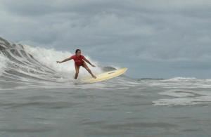 Una donna che cavalca un'onda su una tavola da surf nell'oceano di Burnt Toast Surfcamp a Nosara
