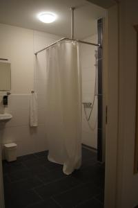 La salle de bains est pourvue d'une douche avec rideau de douche blanc. dans l'établissement Gasthof Schönau, à Heilsbronn