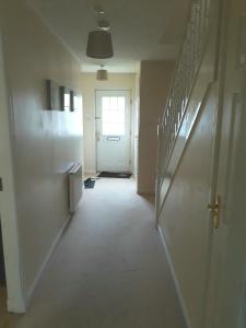 an empty hallway with a white door and stairs at Handy Dale House in Bathgate