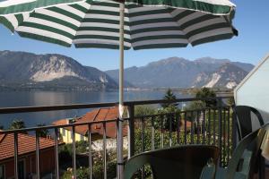 a balcony with an umbrella and a view of the water at Nina & Berto in Verbania