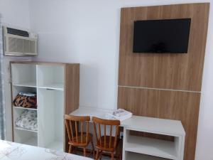 Habitación con escritorio y TV en la pared. en Pousada Terra do Sol, en Itapema