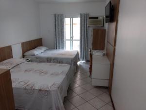 a small room with two beds and a refrigerator at Pousada Terra do Sol in Itapema