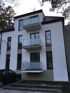 a white house with balconies and a car parked in front at Apartament JULIA in Świnoujście