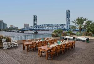 a group of tables and chairs with a bridge in the background at Hyatt Regency Jacksonville Riverfront in Jacksonville