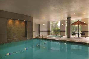 uma grande piscina com um guarda-sol e uma mesa em Hyatt Place College Station em College Station