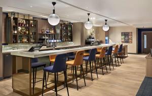 a restaurant kitchen with a bar and chairs at Hyatt Place London Heathrow Airport in Hillingdon