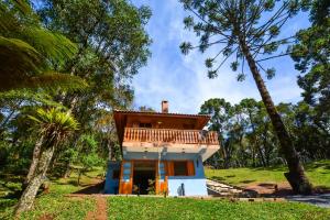 a house in the woods with a balcony at Pousada Bruxa Marela in Monte Verde