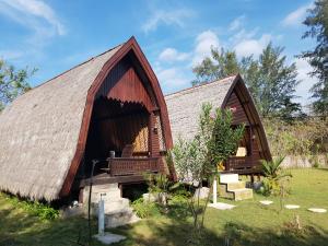 a house with a thatched roof and a yard at Sasak Island Bungalows in Gili Meno