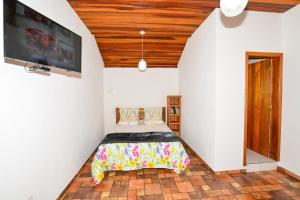 a bedroom with a bed and a flat screen tv at Pousada Bruxa Marela in Monte Verde