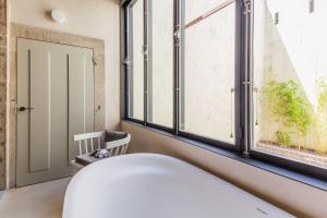 a white bath tub sitting next to a window at Armazém Luxury Housing- Architectural & Design Hotel in Porto