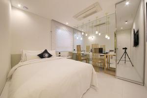 a bedroom with a white bed and a kitchen at Hotel Cullinan 2 Geondae in Seoul