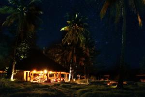a hut with palm trees and lights at night at Gili Asahan Eco Lodge & Restaurant in Gili Asahan