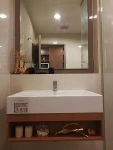 Un baño con un lavabo blanco y un espejo. en SimplyComfy Apartment by Patsamon, en Pattaya South