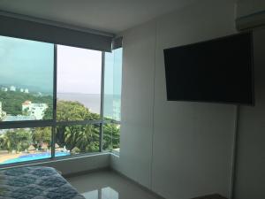 1 dormitorio con TV de pantalla plana en la pared en Costa Azul Suite 606, en Santa Marta