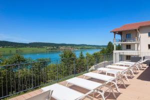 a balcony with lounge chairs and a view of a lake at Hotel Spa Les Rives Sauvages in Malbuisson