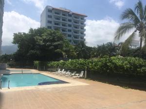 a swimming pool with lounge chairs and a tall building at Costa Azul Suite 606 in Santa Marta