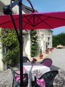- une table avec un parasol rouge sur la terrasse dans l'établissement Chambres d'Hotes Elvire et Laurent Barbey, à Sainte-Marie-du-Mont