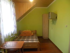 ポランチクにあるPod Kabajkaのベッドとテーブル付きの小さな緑の部屋