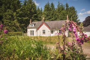 a white house in the middle of a field with flowers at Friars Carse Country House Hotel in Dumfries