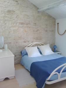 een slaapkamer met een blauw bed en een stenen muur bij la Rosaliere in Chabournay