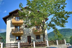 a building with a tree in front of it at Heaven Guesthouse in Corbeni