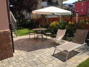 een patio met een tafel en stoelen en een parasol bij Casa Ducati in Riva del Garda