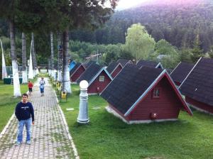 a man standing next to a row of red houses at Vila Bratocea in Cheia