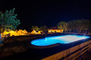a swimming pool at night with tents in the background at Boutique Camping Nono Ban in Gornji Humac
