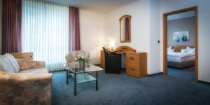 a hotel room with a couch and a chair and a table at Hotel Pfälzer Hof in Braunschweig