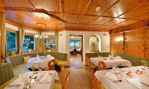 ゼーにあるHotel Enzian Paznaunの白いテーブルと椅子、木製の天井が備わるレストラン